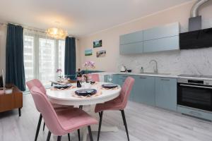 a kitchen with a white table and pink chairs at Plac Unii Apartment Gdynia by Renters in Gdynia