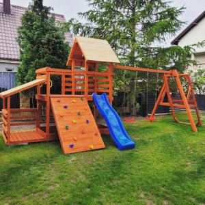 a wooden play set with a slide and a playground at Apartamenty Morski Brzeg - Sauna, Balia in Władysławowo