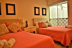 a bedroom with two beds with orange sheets and a window at Kangaroo Wasi Airport Bed & Breakfast in Lima
