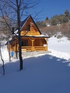 Cabaña de madera con nieve en el suelo en Planinska brvnara, en Kupres