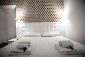 - une chambre avec un grand lit blanc et 2 serviettes dans l'établissement Flowers Apartments, à Rome