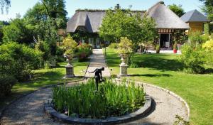 un jardin avec une statue en face d'une maison dans l'établissement LA FONTAINE ROMY, à Genneville