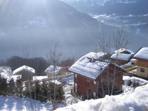 un village recouvert de neige avec des montagnes en arrière-plan dans l'établissement Ski Chalet - Chez Helene Ski fb, à Montagny