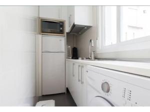 La cuisine blanche est équipée d'un évier et d'un réfrigérateur. dans l'établissement Apartamento Anton Martin II, à Madrid