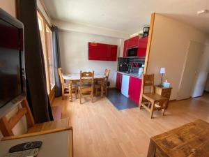 un salon avec une table et une cuisine avec des placards rouges dans l'établissement Appartement Brides-les-Bains, 2 pièces, 5 personnes - FR-1-512-137, à Brides-les-Bains