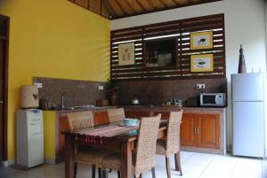 cocina con mesa de madera y nevera blanca en Villa Cantik, en Ubud
