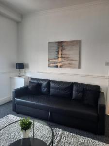 un divano nero in un soggiorno con tavolo di Alexander Apartments South Tyneside 2 a South Shields