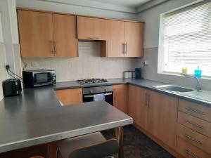 a kitchen with wooden cabinets and a counter top at Alexander Apartments South Tyneside 2 in South Shields