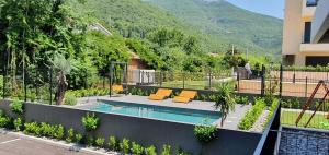 a house with a swimming pool with a mountain in the background at Bjelica Rental Apartments - Nela Apartment in Tivat