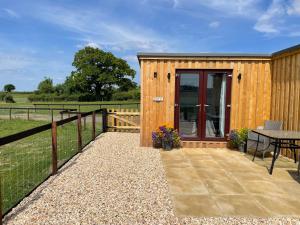 a wooden cabin with a table and a fence at Mallard s Retreat in Blandford Forum