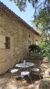 a table and chairs in front of a stone building at Le Pigeonnier, gîte des Lucioles en Provence in Montségur-sur-Lauzon