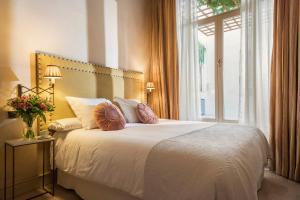 1 dormitorio con 1 cama blanca grande y ventana en CH Apartments Boutique en Sevilla