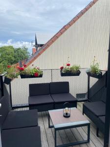 a patio with couches and a table on a balcony at Apartamentai Juodkrantėje Saulės smūgis 2B 65 in Juodkrantė
