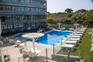 a hotel with a pool and chairs and a building at SALOU 4 YOU apartamentos in Salou