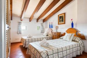 two beds in a room with wooden ceilings at Villa Rafal Fort by Escape Home in Alaior +40 photos