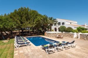 a swimming pool with lounge chairs and a house at Villa Rafal Fort in Alaior
