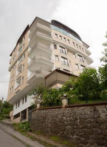 un grand bâtiment blanc avec un mur en pierre dans l'établissement Bengisu suite apart, à Trabzon