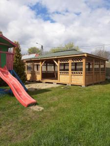 a wooden building with a slide and a playground at Dom Goscinny Luna in Stegna