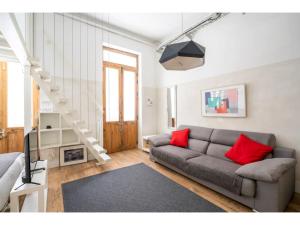 ein Wohnzimmer mit einer grauen Couch und roten Kissen in der Unterkunft Espacioso Loft en Ponzano-Chamberí– Madrid in Madrid