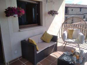 a porch with a couch and a chair on a balcony at Escapada Romantica con Jacuzzi y vistas al Castillo de Trevejo in Villamiel