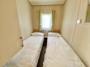 two beds in a small room with a window at Waterside Holiday Park in Goodrington