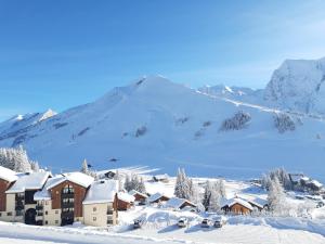 a village covered in snow with a mountain in the background at LE Hameau 001 in Manigod