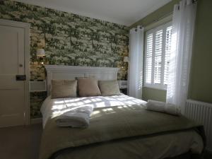 1 dormitorio con 1 cama con papel pintado verde y blanco en Kentwood Guest House, en Arnside
