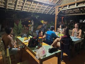 a group of people sitting at tables in a restaurant at Harry's Ocean House Watukarung Homestay in Kalak