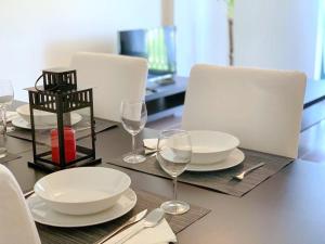 una mesa con platos blancos y copas de vino. en Sónia&Irene Apartments en Setúbal