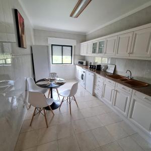 cocina con armarios blancos, mesa y sillas en Sónia&Irene Apartments en Setúbal