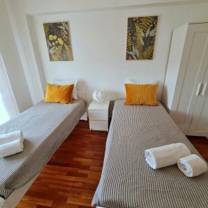 two beds in a room with wooden floors at Sónia&Irene Apartments in Setúbal +15 photos
