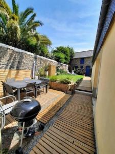 un patio avec une table, des chaises et un grill dans l'établissement LE COCON de MATIGNON Gîte 4 étoiles 5 kms mer, à Matignon