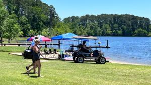 a woman walking past a golf cart next to a lake at Alpine Lakeview Motel Room WiFi,Sandy beach Boat Ramp,Pier,Marina,Bath House with Laundromat in Hemphill
