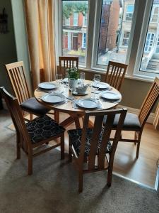 a wooden table with chairs and plates and glasses on it at Woldgate Retreat Bridlington in Bridlington