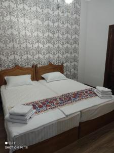Bett mit weißer Bettwäsche und Blumentapete in der Unterkunft Oybinokh hotel in Buxoro