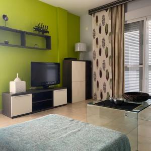 sala de estar con TV y paredes verdes en Residencial Oasis, en Mojácar