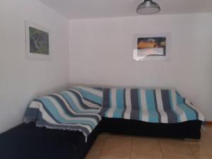 un divano con una coperta a righe sopra in una stanza di Location saisonnière Le Clos des Agrumes a Sainte-Anne