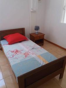 sypialnia z łóżkiem z czerwoną poduszką i stołem w obiekcie Location saisonnière Le Clos des Agrumes w mieście Sainte-Anne