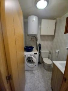 a small bathroom with a washing machine and a toilet at La Casina de Póo de LLanes in Po