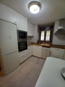 uma cozinha com armários brancos e um forno com placa de fogão em La Casina de Póo de LLanes em Po