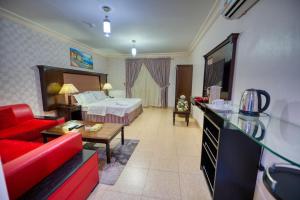 Habitación de hotel con cama y sofá rojo en Al Fanar Al Alami 2- Haya'a malakeya, en Yanbu