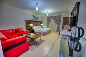 Habitación de hotel con sofá rojo y cama en Al Fanar Al Alami 2- Haya'a malakeya en Yanbu