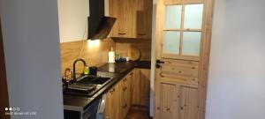 kuchnia z drewnianymi szafkami, zlewem i kuchenką w obiekcie Pod Śnieżnymi Kotłami w Piechowicach
