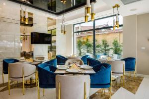 un restaurant avec des tables et des chaises bleues et une grande fenêtre dans l'établissement Onal Boutique Hotelier, à Mamaia