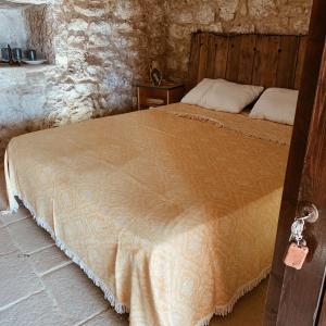 ein Schlafzimmer mit einem Bett in einem Steinzimmer in der Unterkunft Trullo Contrada Stracca in Alliste