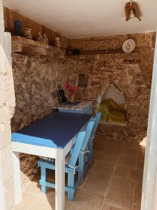 - une table bleue et des chaises dans une pièce dotée d'un mur en pierre dans l'établissement Trullo Contrada Stracca, à Alliste