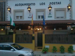 um carro estacionado em frente a um edifício com bandeiras em Alojamiento Los Poetas em Baeza
