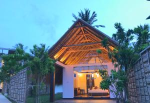 uma casa de hóspedes com telhado de palha e palmeiras em Blue Whale Resort & Kite Surfing em Kalpitiya