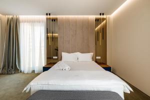- une chambre avec un grand lit blanc et une fenêtre dans l'établissement Onal Boutique Hotelier, à Mamaia