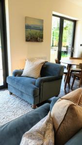 a living room with a blue couch and a table at Finest Retreats - Blackbarn Wood in Balsham